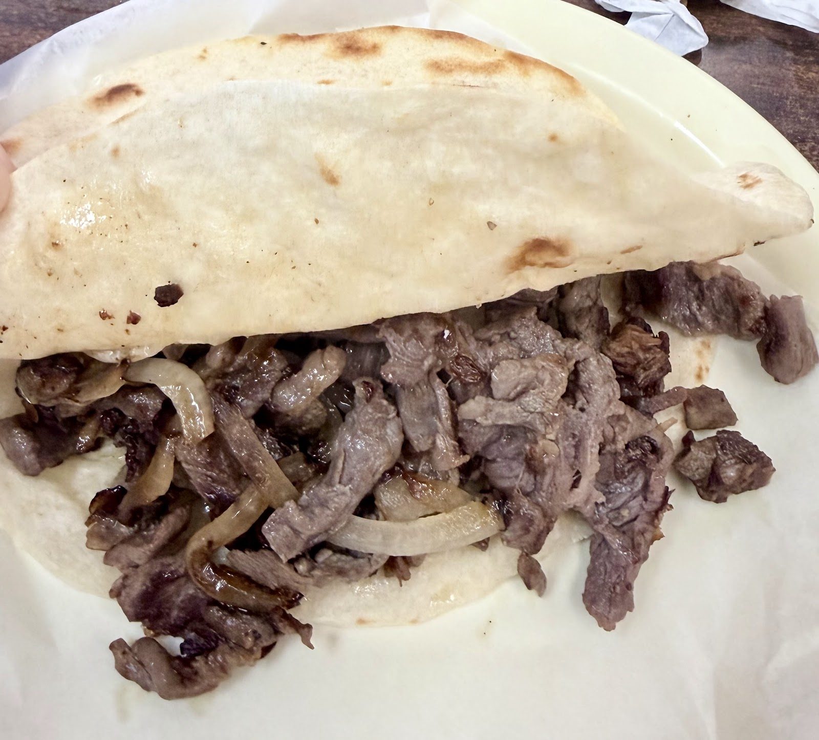 Taco of grilled beef and onions on a large flour tortilla